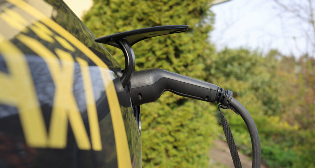 Nahaufnahme eines Elektroautos beim Laden in einer Wallbox.